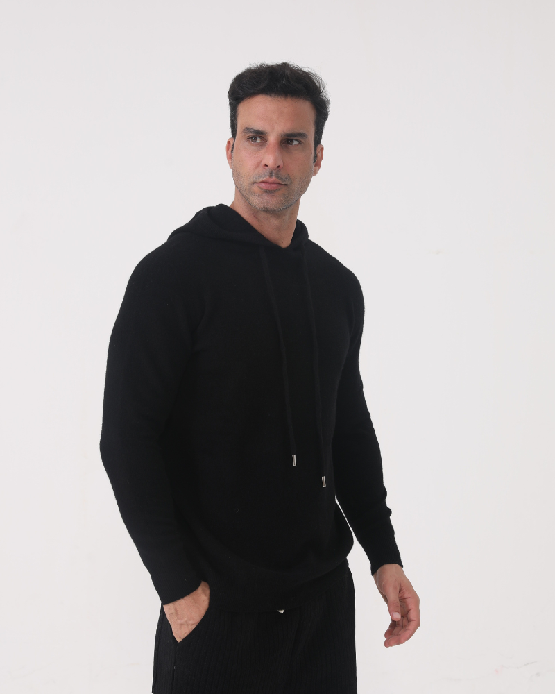 Model in 100% cashmere hoodie in Black – Positano, close-up showing ribbed cuffs and drawstring hood.